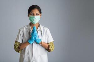 Young woman Doctor doing Namaste because of outbreak of COVID-19. New greeting to avoid the spread of coronavirus instead of greeting with a hug or handshake. photo