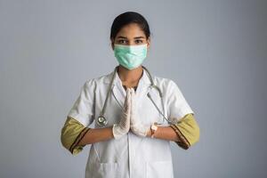 Young woman Doctor doing Namaste because of outbreak of COVID-19. New greeting to avoid the spread of coronavirus instead of greeting with a hug or handshake. photo