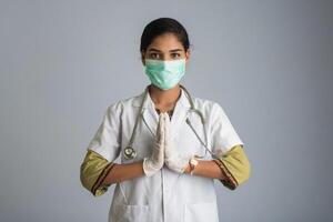 Young woman Doctor doing Namaste because of outbreak of COVID-19. New greeting to avoid the spread of coronavirus instead of greeting with a hug or handshake. photo