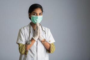 Young woman Doctor doing Namaste because of outbreak of COVID-19. New greeting to avoid the spread of coronavirus instead of greeting with a hug or handshake. photo