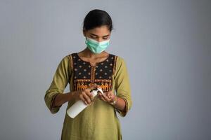 Portrait of young girl using or showing a sanitizing gel from a bottle for hands cleaning. photo