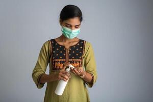 Portrait of young girl using or showing a sanitizing gel from a bottle for hands cleaning. photo