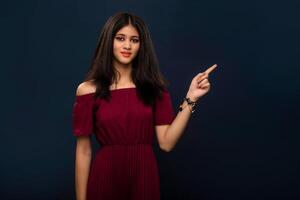 Portrait of a successful cheerful young girl pointing and presenting something with hand or finger with a happy smiling face. photo
