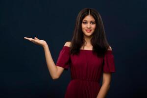 Portrait of beautiful young girl presenting something, showing copy space on her palm on a grey background photo