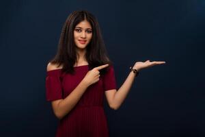 Portrait of beautiful young girl presenting something, showing copy space on her palm on a grey background photo