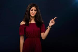 Portrait of a successful cheerful young girl pointing and presenting something with hand or finger with a happy smiling face. photo