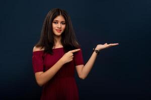 Portrait of beautiful young girl presenting something, showing copy space on her palm on a grey background photo