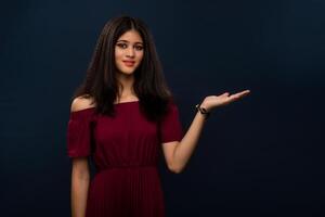 Portrait of beautiful young girl presenting something, showing copy space on her palm on a grey background photo