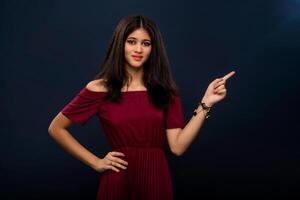 Portrait of a successful cheerful young girl pointing and presenting something with hand or finger with a happy smiling face. photo