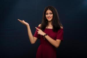 Portrait of beautiful young girl presenting something, showing copy space on her palm on a grey background photo