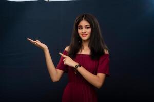 Portrait of beautiful young girl presenting something, showing copy space on her palm on a grey background photo