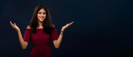 Portrait of beautiful young girl presenting something, showing copy space on her palm on a grey background photo