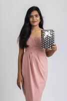 Portrait of a pretty young girl posing with gift box on grey background. photo