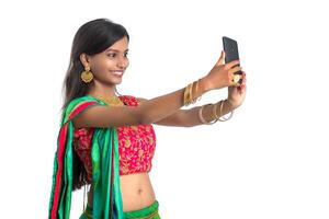 Young Indian girl using a mobile phone or smartphone, talking selfie or talking on chat isolated on a white background photo
