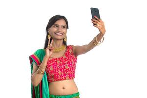 Young Indian girl using a mobile phone or smartphone, talking selfie or talking on chat isolated on a white background photo