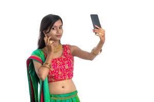 Young Indian girl using a mobile phone or smartphone, talking selfie or talking on chat isolated on a white background photo