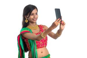 Young Indian girl using a mobile phone or smartphone, talking selfie or talking on chat isolated on a white background photo