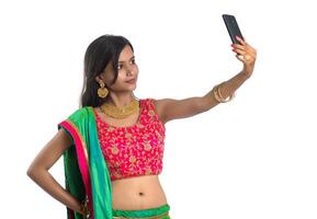 Young Indian girl using a mobile phone or smartphone, talking selfie or talking on chat isolated on a white background photo