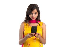 Young Indian girl using a mobile phone or smartphone isolated on a white background photo