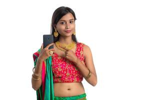 Young Indian traditional girl using a mobile phone or smartphone isolated on a white background photo