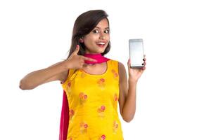 Young beautiful woman holding and showing blank screen smartphone or mobile or tablet phone on a white background. photo