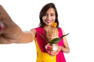 Beautiful young happy girl taking selfie with Kalash using a camera or smartphone on a white background photo