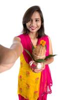 Beautiful young happy girl taking selfie with Kalash using a camera or smartphone on a white background photo