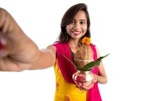 Beautiful young happy girl taking selfie with Kalash using a camera or smartphone on a white background photo