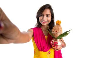 Beautiful young happy girl taking selfie with Kalash using a camera or smartphone on a white background photo