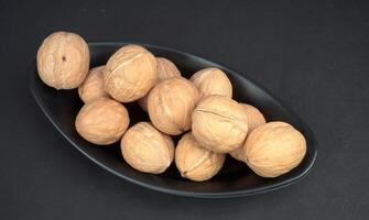 Walnut in black oval shape bowl with black background photo