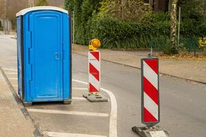 Mobile toilet placed on street during roadworks with warning signs photo