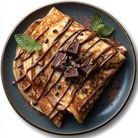 Chocolate crepe on plate top view isolated on white background with shadow. Chocolate pancake dessert on ceramic plate photo