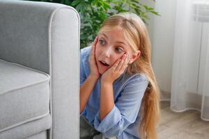 The girl is hiding behind the sofa and eavesdropping on someone else's conversation. photo