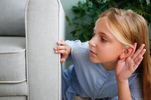 The girl is hiding behind the sofa and eavesdropping on someone else's conversation. photo