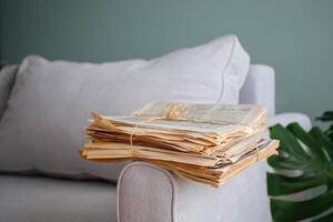 A stack of newspapers is lying on the grey sofa. photo