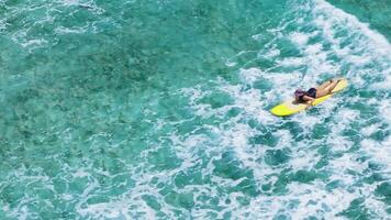 Drone view of female surfer paddling on surfboard in ocean video