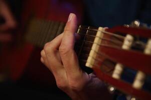 Close-up of hands playing an acoustic guitar, showcasing finger placement and chord strumming for an intimate and artistic musical moment photo