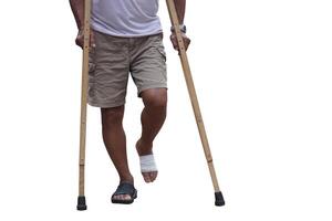 Close up man walking with wooden crutches because of injury on foot. White background. Concept, Medical equipment for helping disabled people or patients with symptom of walking problems. photo