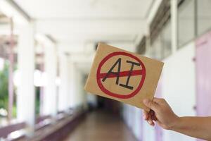 Close up hand holds paper card with No AI, prohibition sign, outdoor nature background. Concept, disagree, anti or don't support to use AI or Artificial Intelligence in daily life. photo
