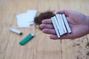 Close up hand holds handmade tobacco cigarettes, equipment for smoking. Concept, smoking is bad for health, cause health problems respiratory disease and addict. photo