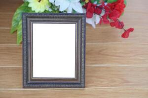 Photo frame on wooden floor, decorated with flowers behind. Copy space for adding text or photos. Concept, Proud, memories and nostalgia. Exhibition, art gallery. Photography.
