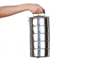 Hand holds tiffin carrier stainless steel lunch box on white background. Concept, Reuse and washable food container, campaign for using food box, helps reduce global warming from using plastic bag. photo