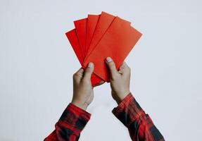 Hand holding red packet or red envelope isolated on white background. Chinese New Year or Lunar New Year concept. photo