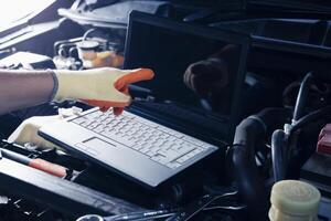 Car inspection service using a modern computer system. and a modern mechanic in the garage Auto mechanics use computer software to check two engines are running and repair them. photo