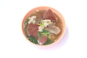 Pork blood jelly soup with entrials and vegetable in light orange ceramic bowl on white background. photo