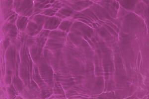Transparent pink clear water surface texture with ripples, waves and rings in sunlight. photo