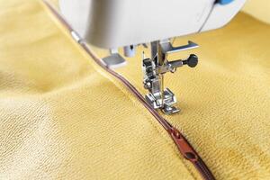 Modern sewing machine with yellow velours fabric close up photo