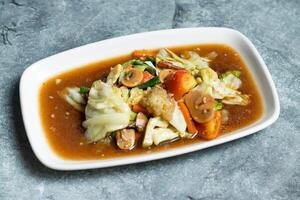 Mixed Stir fry Vegetables including cabbage, cauliflower, mushroom, carrot, tomato and green chilli served in tray dish isolated on grey background side view of thai food photo