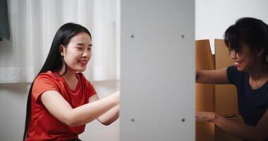Handheld shot, Two siblings are happily chatting while assembling furniture together in the living room of their new house. Moving to a new home concept video