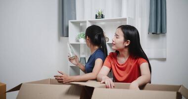 Handheld high angle view shot, Two siblings happily sit on the floor talking as they unpack belongings from boxes to decorate a room in new home. Moving to a new home concept video